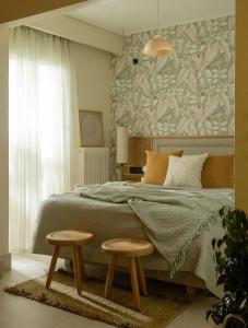 阿格里尼翁Agrinio ART Suites的一间卧室,配有一张床铺,旁边设有两张凳子