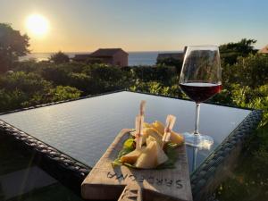 帕拉迪索海岸Villetta La Risacca的一张桌子,上面放着一杯葡萄酒和一盘食物
