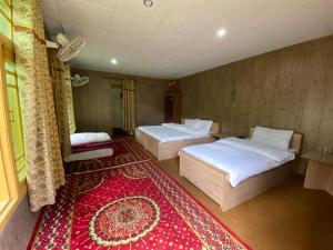 罕萨Tourist Cottage Hunza的一间设有两张床的房间和红色地毯