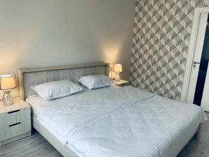 撒马尔罕Yas Apartment的一张带两个白色枕头的床和两个床头柜