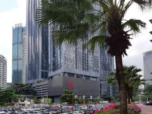 吉隆坡Star Luxury Suites KLCC的一座有停车车的建筑前的棕榈树