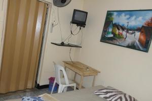 马那瓜Hostal Nicaragua Guest House的一间卧室配有一张桌子和一台墙上的电视。