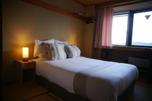 妙高Red Fox Lodge Myoko的一间卧室配有一张带灯和窗户的床