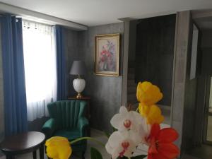埃格尔Filsdeger Royal Panzió的客厅配有绿色椅子和鲜花