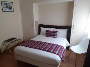 阿朗松乐查普罗格酒店的一间卧室配有一张床,床上有条纹毯子
