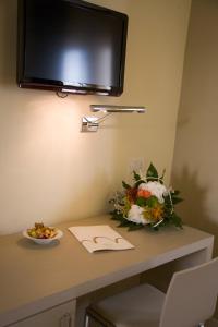 洛雷托圣弗朗西斯酒店的一张桌子,上面放着一碗鲜花,墙上放着一台电视机