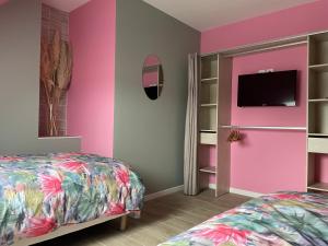 维莱科特雷圣雷米度假屋的一间卧室设有粉红色的墙壁、一张床和电视