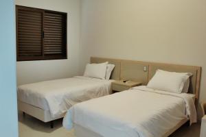 库尔韦卢Good Stone Curvelo Hotel的配有白色床单和窗户的客房内的两张床