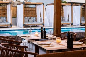 斯基亚索斯镇Skiathos Theros, Philian Hotels and Resorts的游泳池旁的桌子上摆放着葡萄酒瓶