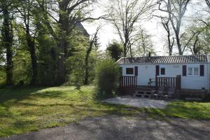 苏莱讷迪Camping La Croix Badeau的白色小屋,在草地上设有长凳