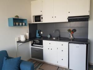 鲁瓦扬Appartement Royan, 200 m de la PLAGE的小厨房配有白色橱柜和蓝色沙发
