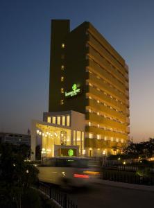 浦那Lemon Tree Hotel Hinjewadi Pune的一座在晚上有绿色标志的建筑