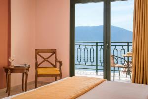 凯法利尼亚岛Kefalonia Bay Palace的一间带一张床和一把椅子的卧室以及一个阳台