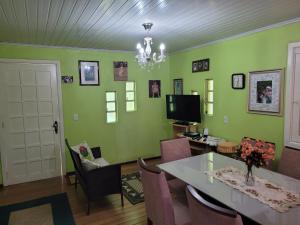 新彼得罗波利斯lugar tranquilo aconchegante perto da natureza的一间拥有绿色墙壁和桌椅的用餐室