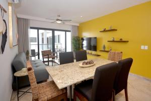 普拉亚卡门IPANA Luxury Apartments by Vacaciones.Yeah的用餐室设有黄色的墙壁和桌椅