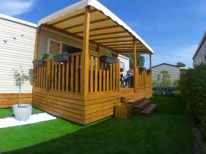 鲁西隆地区卡内Mobil home moderne neuf et ultra équipé de 6 à 8 couchages的木制凉亭,在草地上设有甲板