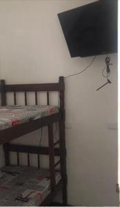 圣保罗Augusta Jardins Home的挂在床边墙上的平面电视