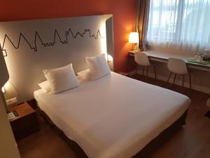 卡尔卡松Kyriad Carcassonne - Aéroport的卧室配有一张带两个枕头的大白色床
