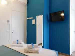 佛罗伦萨Porta alla Croce Guest House的一间设有蓝色墙壁和一张带毛巾的床的客房