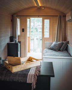 金洛伊Glamping - 25 min Roermond, Maasmechelen & Maastricht的客房设有床、桌子和窗户。