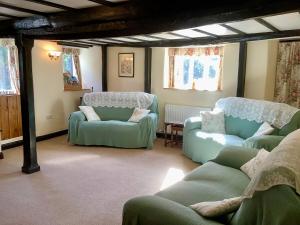 锡德茅斯The Barn and Pinn Cottage的客厅配有绿色椅子和沙发