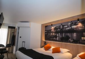 昂热Logis Hôtel Angers Sud的酒店客房设有一张床,墙上挂有绘画作品