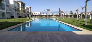 西迪拉哈尔Casabay Appart Vue Sur Piscine的棕榈树公园和建筑中的游泳池