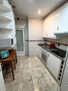 萨拉曼卡Luxury Family Homes K的厨房配有白色橱柜和木桌