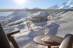 索尔登Hotel Edelweiss Hochsölden Superior的一杯在滑雪场前的桌子上喝的葡萄酒