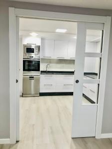 卢戈Apartamento Muralla的厨房配有白色橱柜和不锈钢用具