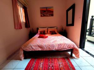 马拉喀什Riad Nour Travel-Les Riads Nour Resorts的一间卧室配有一张红色棉被的床