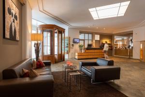 锡尔斯玛丽亚Arenas Resort Schweizerhof的带沙发的客厅和背景行走的人