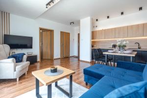 斯克拉斯卡波伦巴Apartamenty Aparts4U的一间带蓝色沙发的客厅和一间厨房