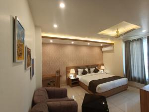德拉敦Hotel Royal Palm Dehradun的酒店客房,配有一张床和两把椅子