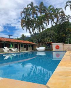 乌巴图巴Hotel Pousada Nosso Cantinho的一座棕榈树游泳池和一座建筑