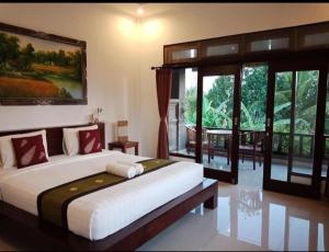 乌布Putra Bisma Guesthouse的一间卧室设有一张大床和一个大窗户