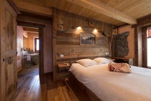 瓦托内切La Luge的一间带一张大床的卧室,位于带木墙的房间