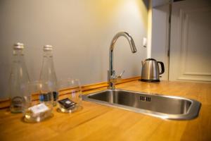 米科瓦伊基Apartamenty Pod Zegarem的厨房水槽,在柜台上配有瓶子和玻璃杯