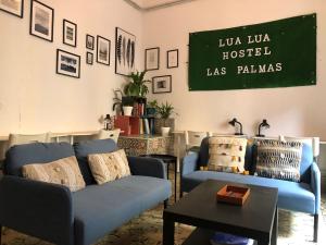 大加那利岛拉斯帕尔马斯卢阿 - 卢阿拉斯帕尔马斯旅舍的客厅配有蓝色的沙发和墙上的黑板