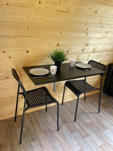 EnscherangeTiny rooms @ camping val d'Or的一张黑桌,配有两把椅子和一张桌子,还有两个盘子