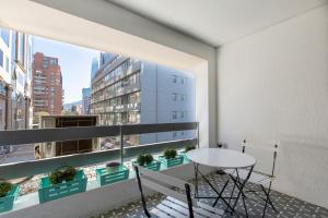 圣地亚哥Apartment - El Golf - Costanera Center的阳台配有桌椅和窗户。