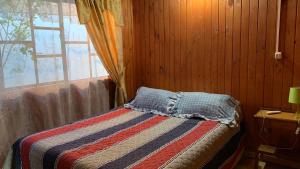 Cabaña Salto del Laja的一间卧室配有一张带毯子的床和窗户