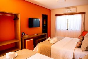 CoqueiroPousada das Flores的酒店客房设有两张床和电视。