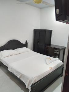 Puerto BerríoHOTEL DORADO PUERTO BERRIO的一间卧室配有一张带黑色床头板和一张桌子的床。
