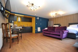 切尔滕纳姆Beechurst Serviced Apartments的一间卧室配有一张床和一张紫色的沙发,还设有一间厨房