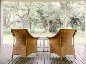 卢萨卡里拉依山林小屋的门廊上设有两把藤椅和一张桌子
