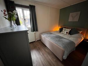 代讷坎普Fijne plek met eigen bos 2000m2 en GRATIS linnen en handdoeken!!的一间卧室,配有一张床和花瓶