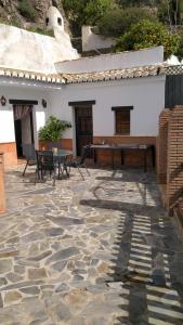 莫纳奇尔Casa Cueva Sierra Nevada - Monachil的石头庭院配有桌子和钢琴