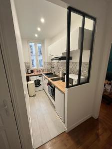 圣芒代Un appartement authentique à deux pas de Paris .的厨房配有水槽和炉灶 顶部烤箱