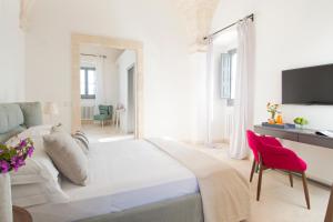 法萨诺Masseria San Giovanni - Epoca Collection的白色卧室设有一张大床和一张红色椅子